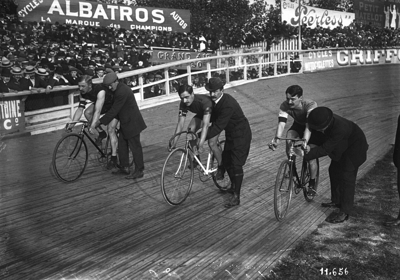 1890s track cycling on a velodrome, riders on fixed-gear bicycles.